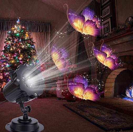 Outdoor Christmas decoration LED laser projector displaying colorful butterfly patterns indoors near a decorated Christmas tree.